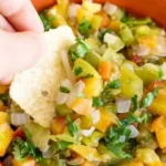 Roasted tomatillo and peach salsa served in a bowl with fresh herbs
