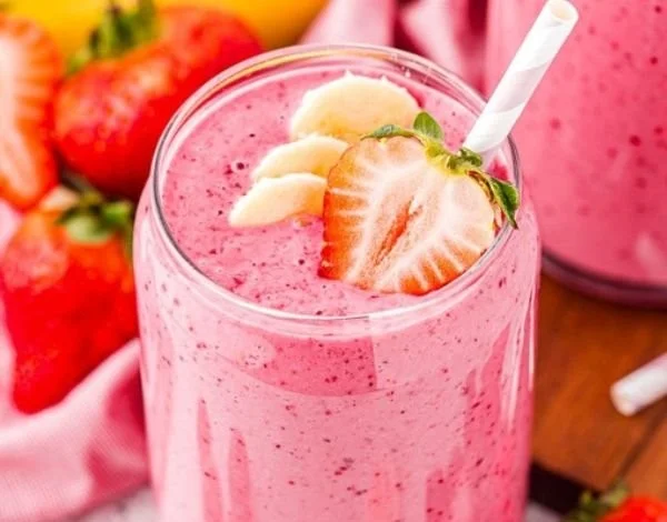 Delicious strawberry banana smoothie in a glass with fresh fruit on the side.