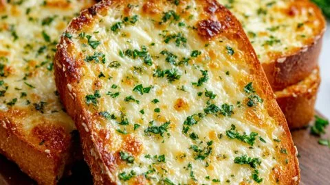 Toasted cheesy garlic bread slices on a plate, golden and delicious.